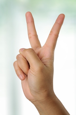 Woman hand gesturing peace with blurry office backgroundの写真素材