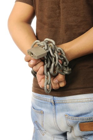Man's hands tied with chains. The man wearing shirt and jeansの写真素材