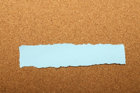 Blue torn piece of paper over brown backgroundの写真素材