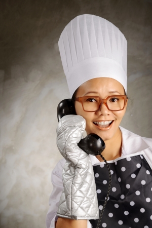 Funny woman chef calling by old phone. This is food delivery conceptの写真素材