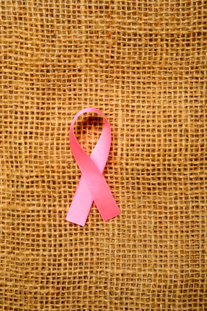 Breast cancer awareness concept. Pink ribbon on burlap backgroundの写真素材