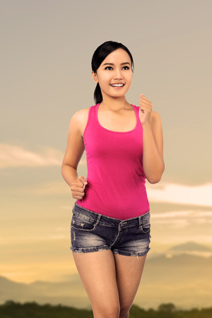 Running asian woman in the sunset backgroundの写真素材