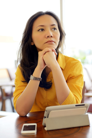 Young woman in cafe holding tablet and feel confusedの写真素材