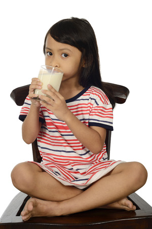 Cute Little Asian Girl Drinking Milk Isolated On White Backgroundの写真素材