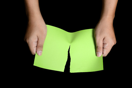 Hand tearing green paper isolated over white backgroundの写真素材