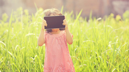 Happy asian girl playing with tablet at outdoor in sunny day with retro style. You can put your...