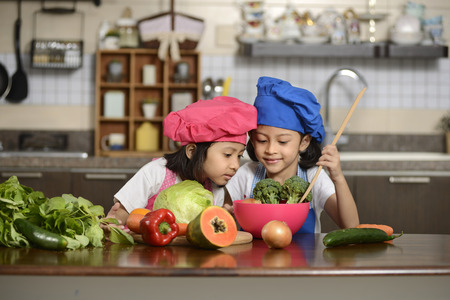 Two little girls, preparing healthy food, in the kitchenの写真素材