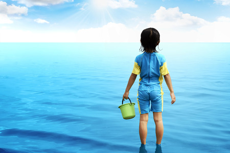 Back view of little girl looking the ocean. Vacation concept imageの写真素材