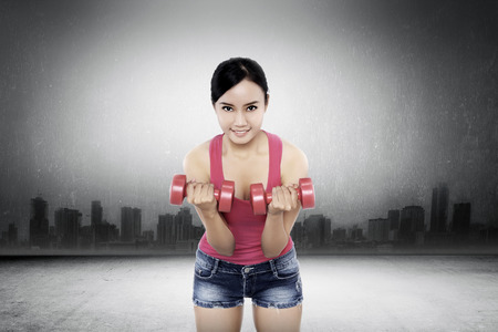 Woman exercise with dumbell with cityscape conceptの写真素材