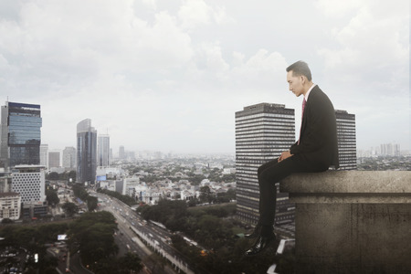 Business man sitting on building rooftop. の写真素材
