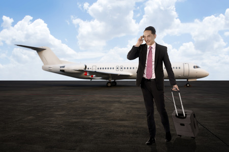 Man walking while calling on the cellphone after arriving with plane. Business travel conceptの写真素材