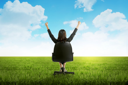 Asian woman sitting on chair on green grass fieldの写真素材