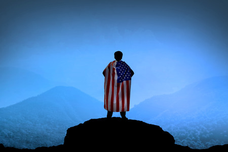 Silhouette of man wearing USA flag as cape on mountain. Patriot conceptualの写真素材