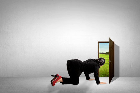 Business woman take a peek through small door, looking for vacation opportunityの写真素材