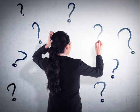 Business woman write question mark on the wall. She dont know what to write