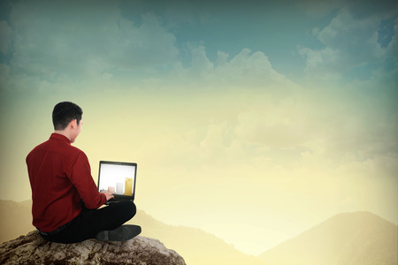 Asian business man working with laptop on the top of the mountainの写真素材