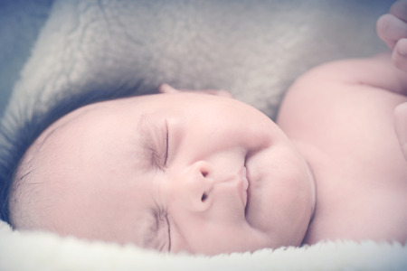 Peaceful baby lying on a bed while sleeping in a bright room over white sheetの写真素材