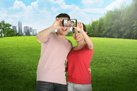 Asian couple doing selfie on city park. Couple travel conceptの写真素材