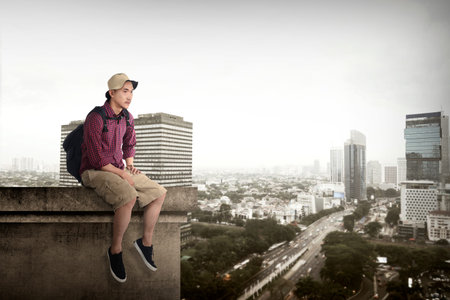 Asian travel man sitting on the rooftop of the building in jakarta