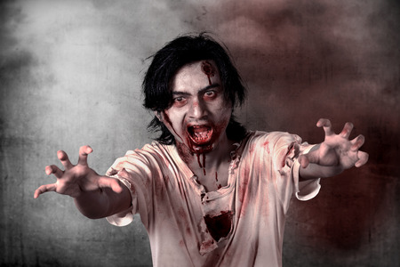Creepy male zombie standing over grunge backgroundの写真素材