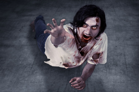 Male zombie crouching on the floor. Halloween conceptの写真素材