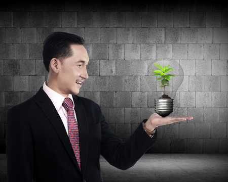 Business person holding light bulb with plant inside. Green energy conceptの写真素材