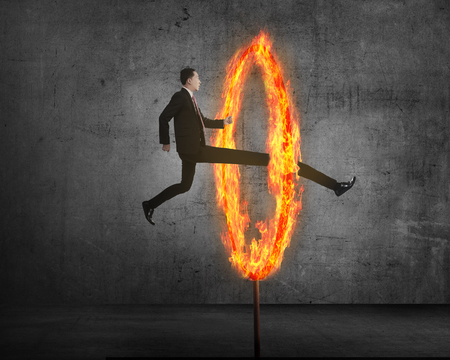 Long leg asian business person jumping through ring of fire. Business risk conceptualの写真素材