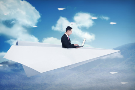 Asian business man working on paper plane on the skyの写真素材