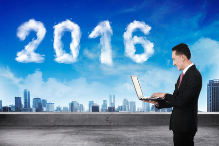 Business person working with laptop with 2016 cloud shape on the sky. New year concept