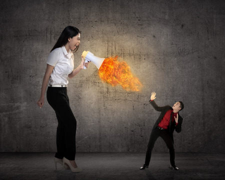 Big boss yelling to her employee with megaphone on fire. Work pressure conceptの写真素材