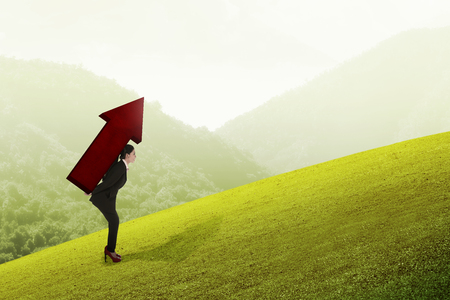 Asian business woman carry big red arrow on her back. Business difficulty conceptの写真素材