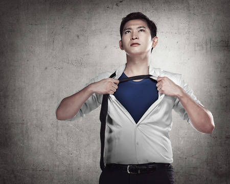 Asian business man showing a superhero suit underneath his suitの写真素材