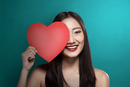 Pretty asian woman holding red paper with heart shape. Valentine day conceptの写真素材