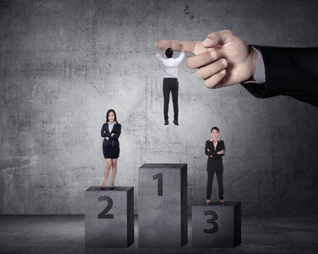 Asian business person hanging on the large hand. Help on business promotionの写真素材