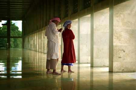 Two religious muslim man praying together inside the mosqueの写真素材