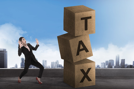 Asian business woman shock looking tax block. Tax calculation conceptの写真素材