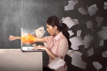 Business woman get angry with her job. She punch her laptop