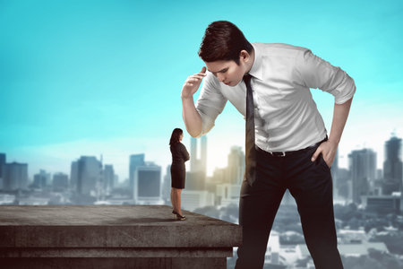 Giant business man looking at small business womanの写真素材