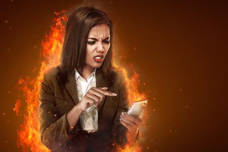 Asian business woman angry looking text on her cellphoneの写真素材