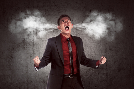 Image of young asian businessman in anger. Smoke out from his earsの写真素材