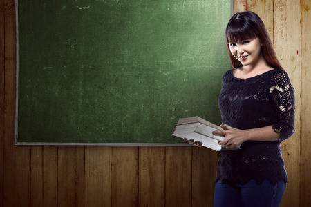 Asian student standing in front of blackboard background. You can put your design on the boardの写真素材