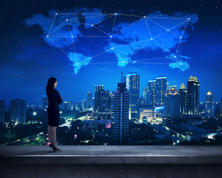 Asian business person standing on the rooftop looking cloud shape world map and starsの写真素材