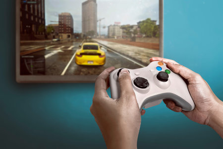 Hand holding game console controller playing racing game on the television