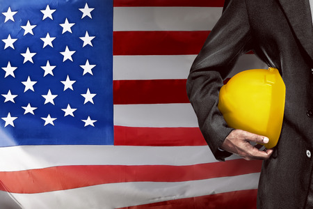 Hand or arm of engineer hold yellow plastic helmet for worker. Labor day conceptの写真素材