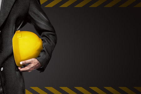 Hand or arm of engineer hold yellow plastic helmet for worker. Labor day conceptの写真素材