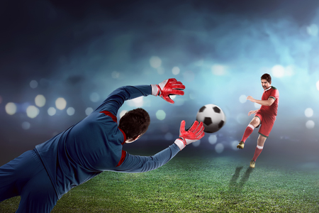 Football player kick ball and goalkeeper try to catchの写真素材