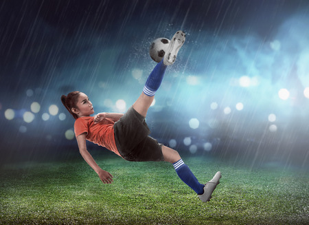 Asian woman football player kick ball on the stadium