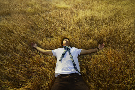 Young asian man relaxing on savanna at sumba island indonesiaの写真素材