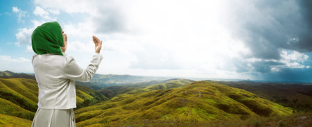 Young muslim woman praying standing on mountainの写真素材
