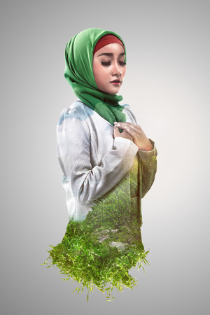 Image of double exposure muslim woman with green grass and blue skyの写真素材